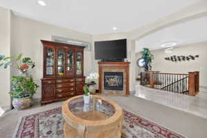 Living room featuring a high end fireplace, arched walkways, recessed lighting, and light tile patterned flooring