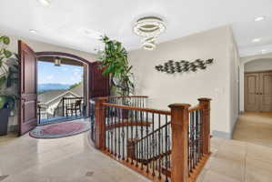 Corridor with recessed lighting, arched walkways, light tile patterned flooring, a mountain view, and an upstairs landing