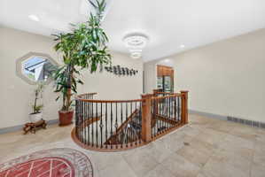 Hall featuring an upstairs landing, arched walkways, and recessed lighting