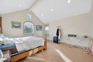 Vaulted ceiling with exposed beam, recessed lighting, arched window, and transom window