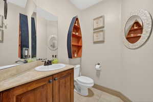 Bathroom featuring a wood-finish vanity with a light-toned countertop, an oval undermount sink, and a bronze-finish faucet