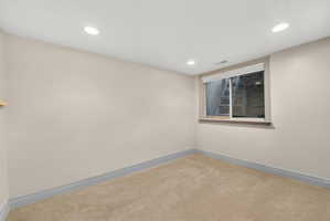 Recessed lighting illuminating a neutral-toned room with carpeted flooring