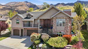 View of front of property featuring stone siding, stucco siding, a mountain view, and an attached garage