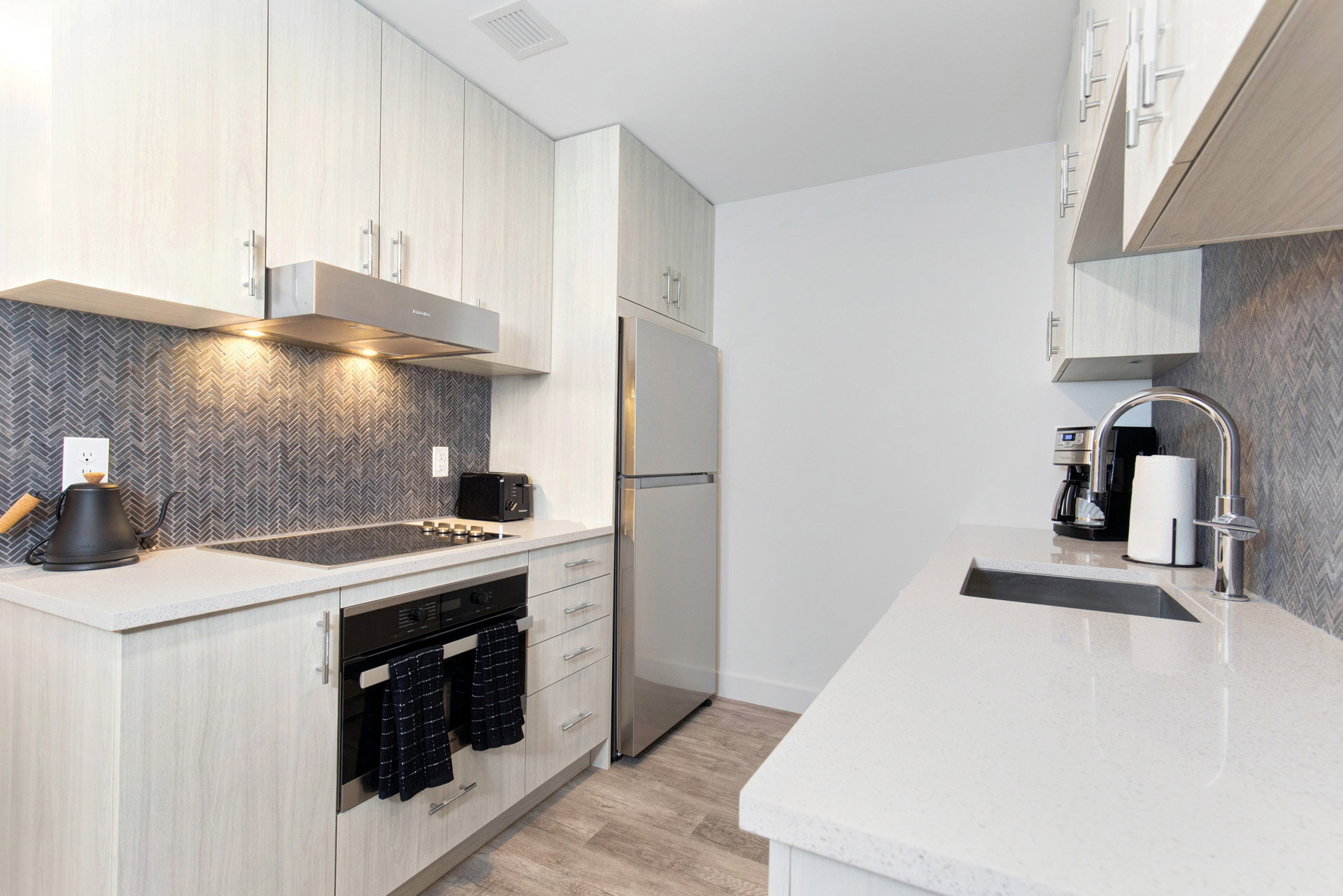 Kitchen with oven, light stone counters, freestanding refrigerator, light wood-type flooring, and tasteful backsplash