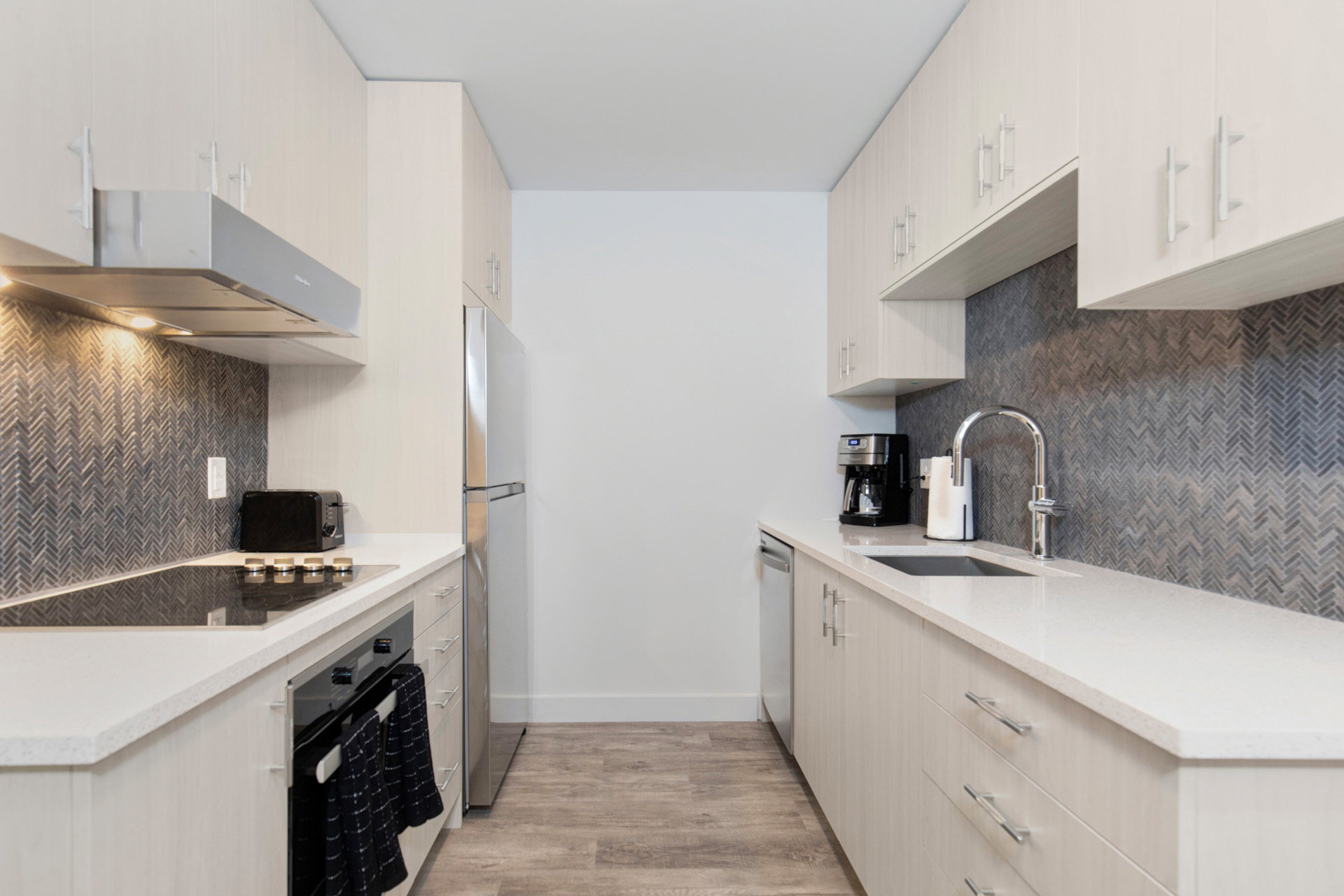 Kitchen featuring light wood-style floors, oven, light stone counters, backsplash, and freestanding refrigerator
