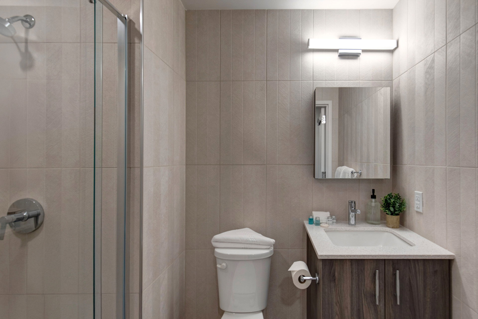 Full bath featuring vanity, a stall shower, and tile walls