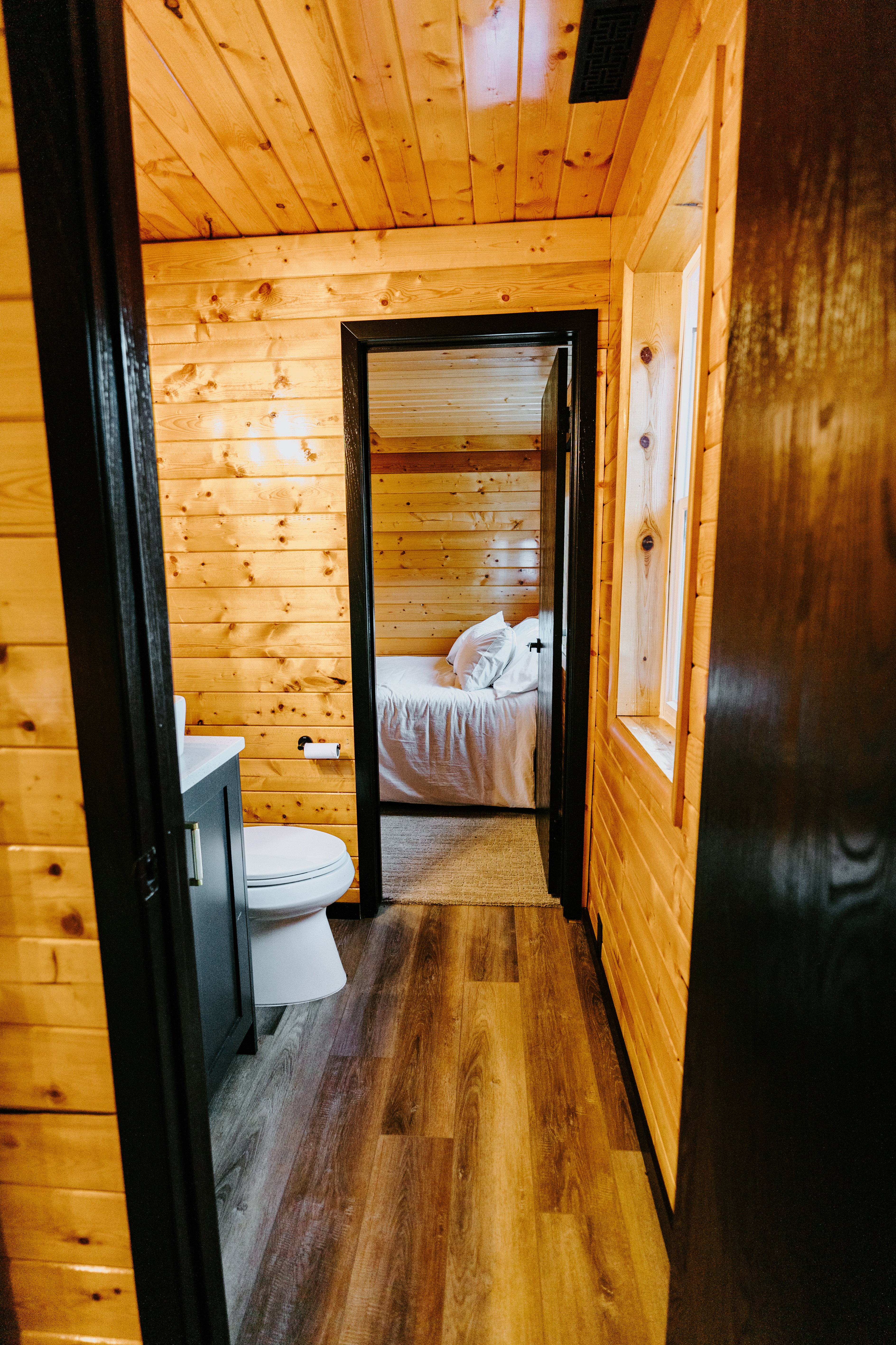Ensuite bathroom featuring wooden walls, dark wood finished floors, wooden ceiling, and vanity