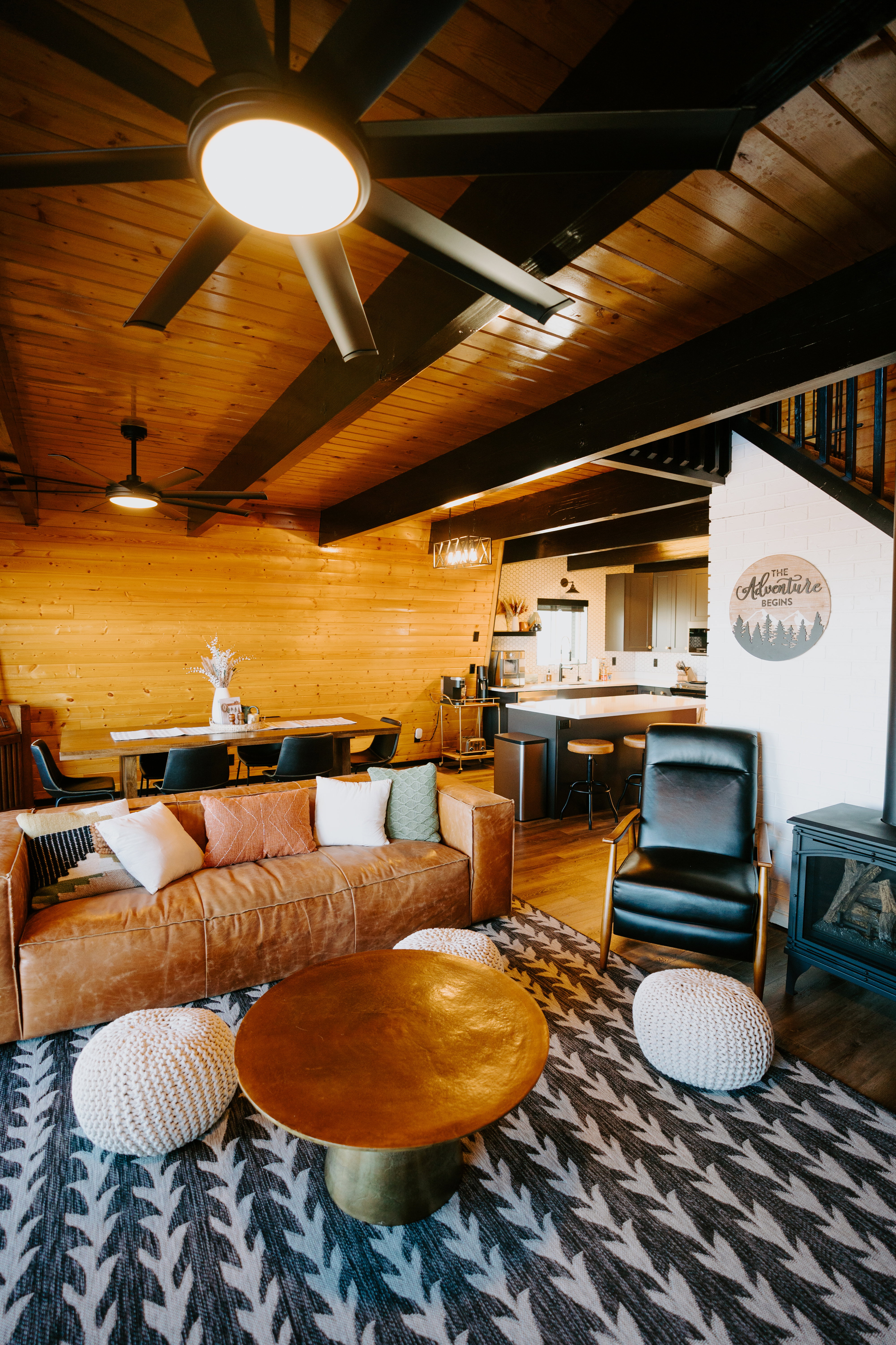 Living room with a wood stove, wood finished floors, a wooden ceiling with exposed beams, and wood walls