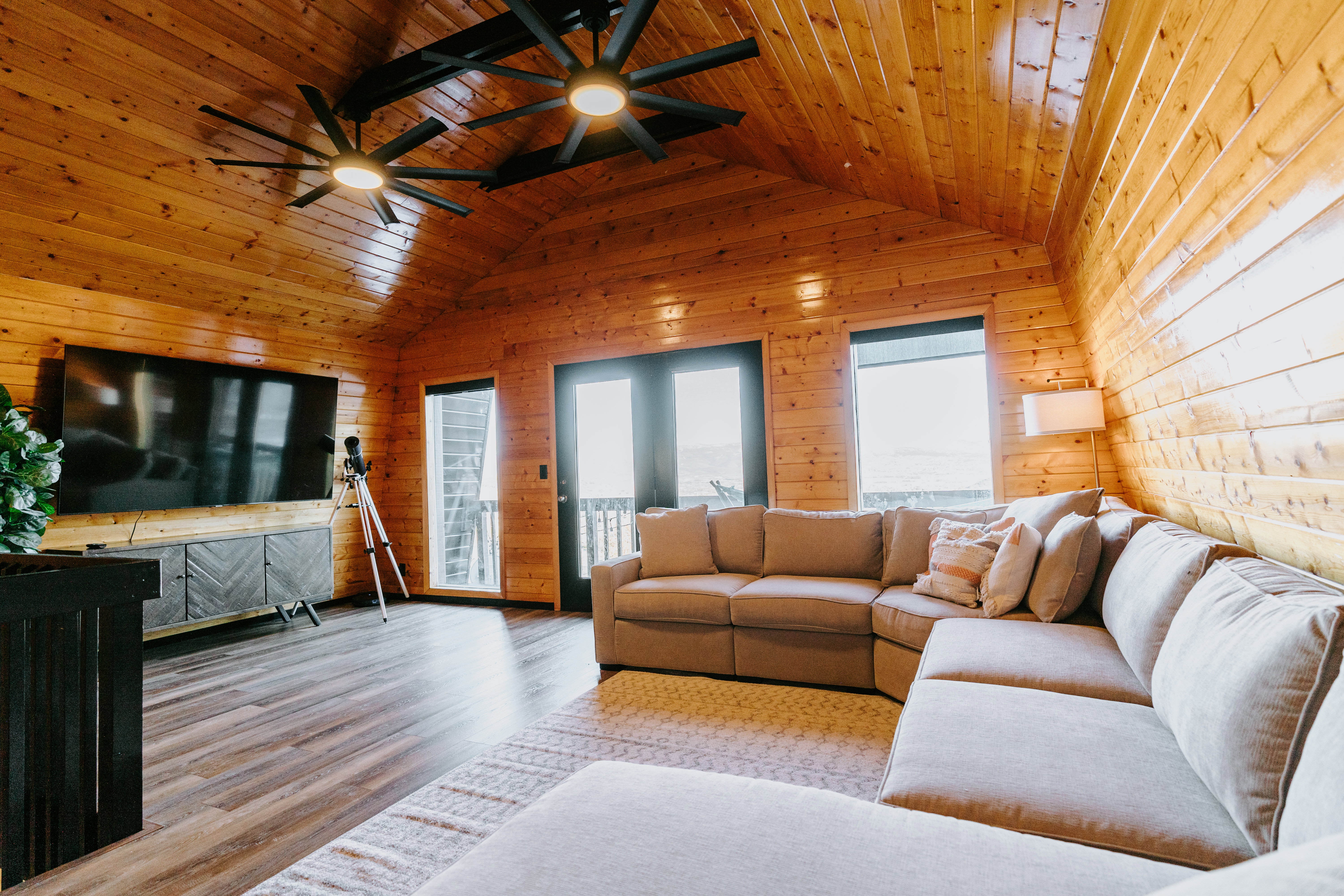 Living room featuring ceiling fan, wood finished floors, wooden walls, and wooden ceiling