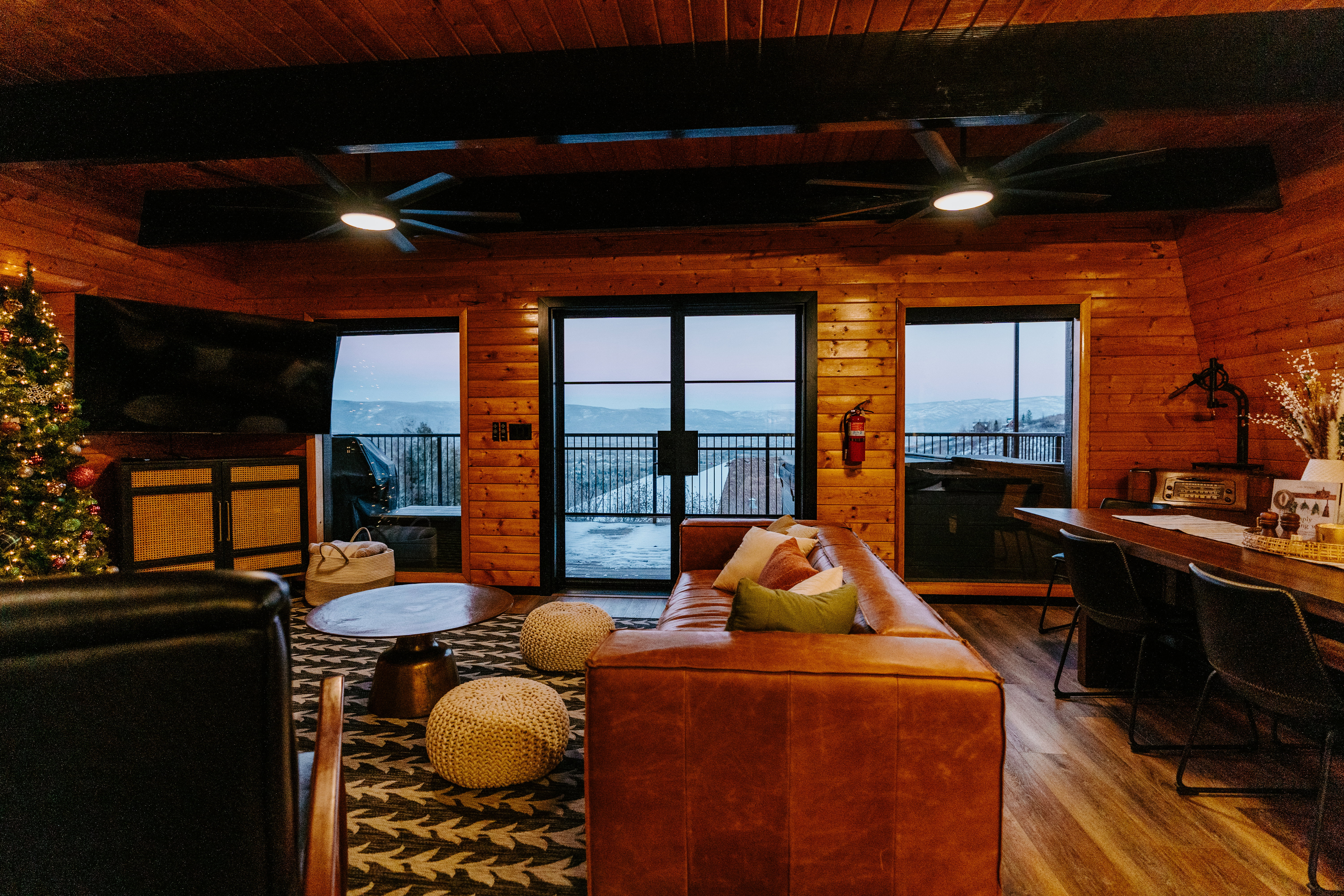 Living area featuring a ceiling fan, wood walls, dark wood finished floors, and a wood ceiling with exposed beams
