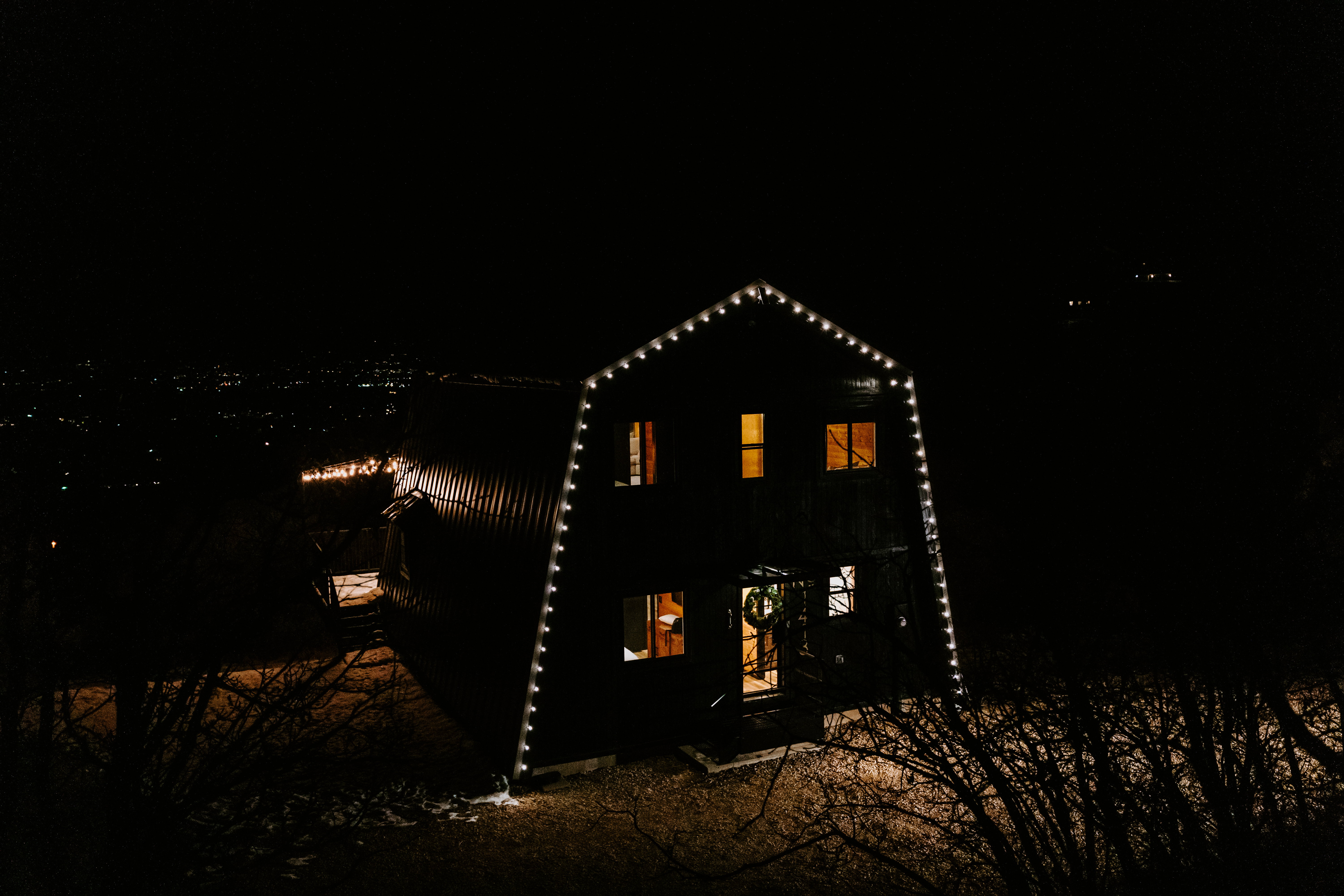Back of house at twilight with a gambrel roof and a patio area