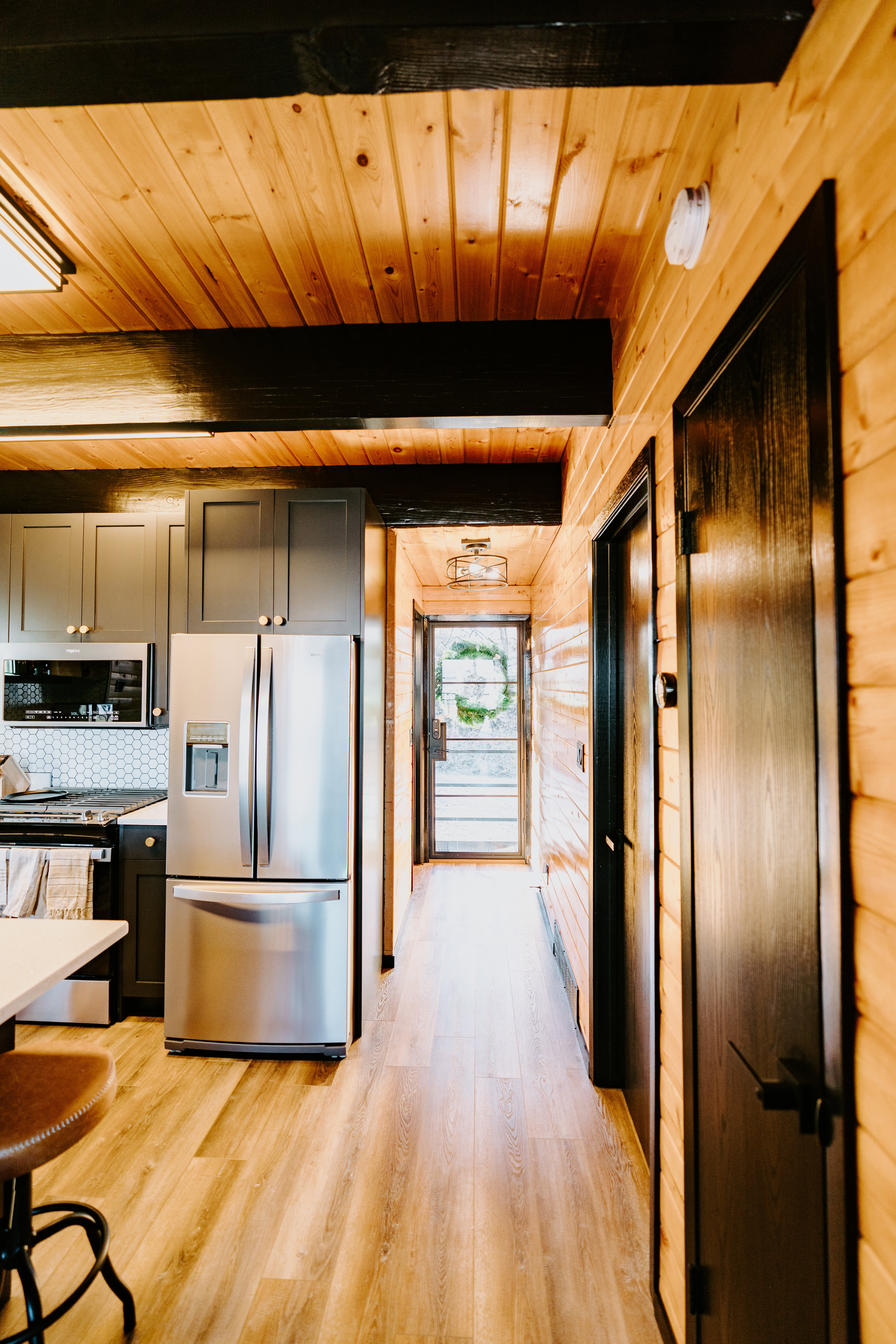 Kitchen with stainless steel appliances, light wood-style flooring, gray cabinets, a wooden ceiling with exposed beams, and light stone countertops