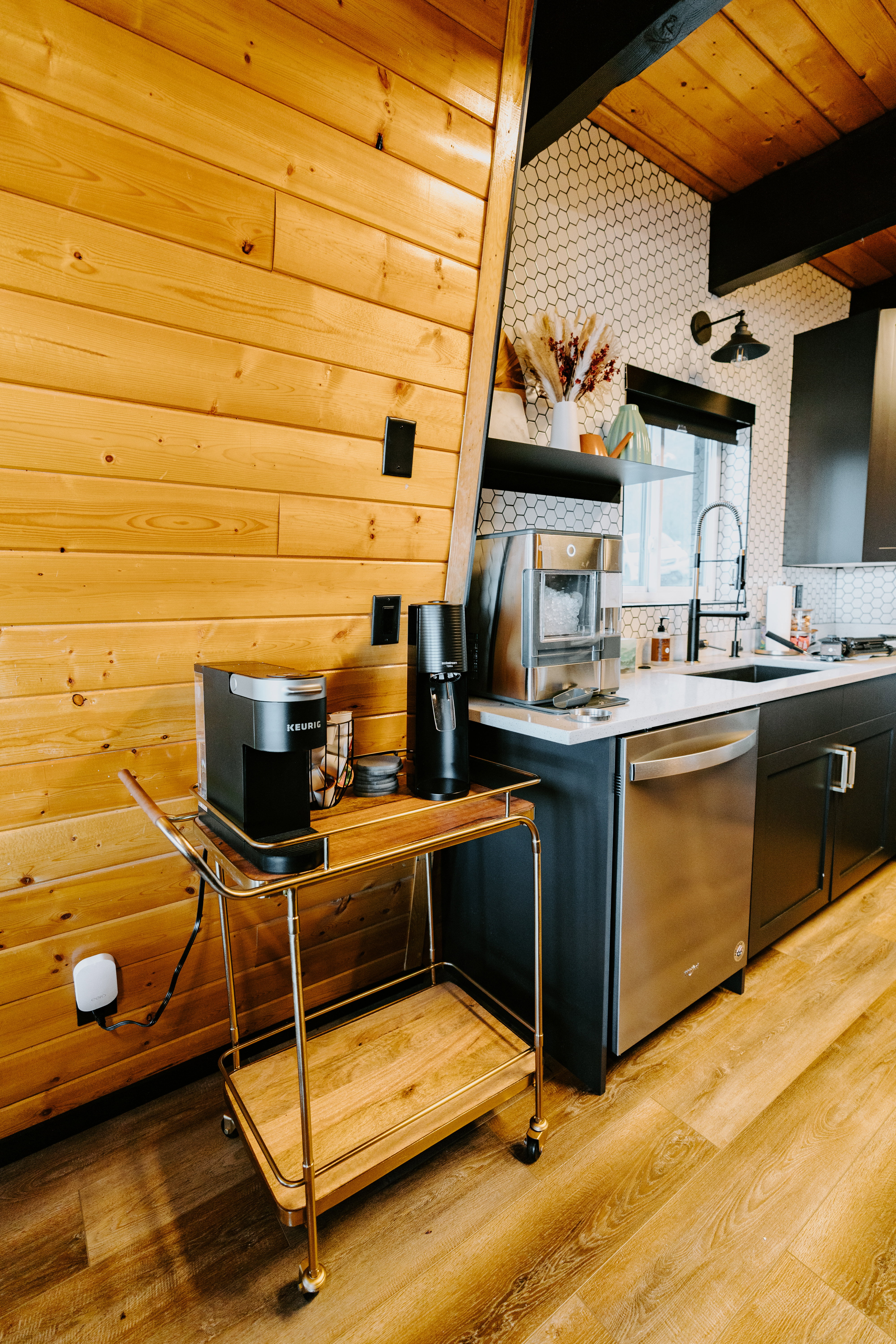 Kitchen with light wood finished floors, a wooden ceiling with exposed beams, dishwasher, and light stone countertops