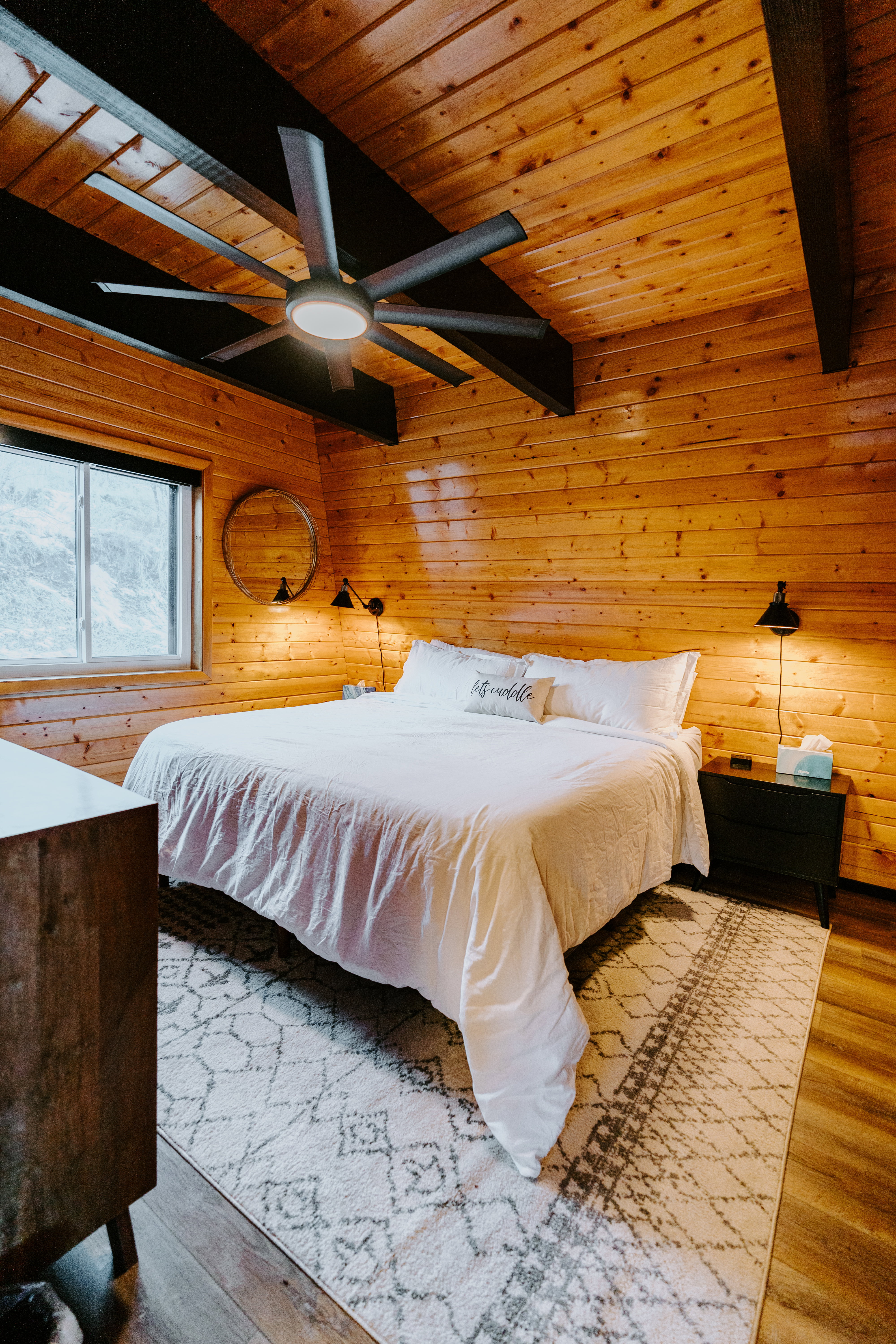 Bedroom with a wooden ceiling with exposed beams, wood walls, a ceiling fan, and wood finished floors
