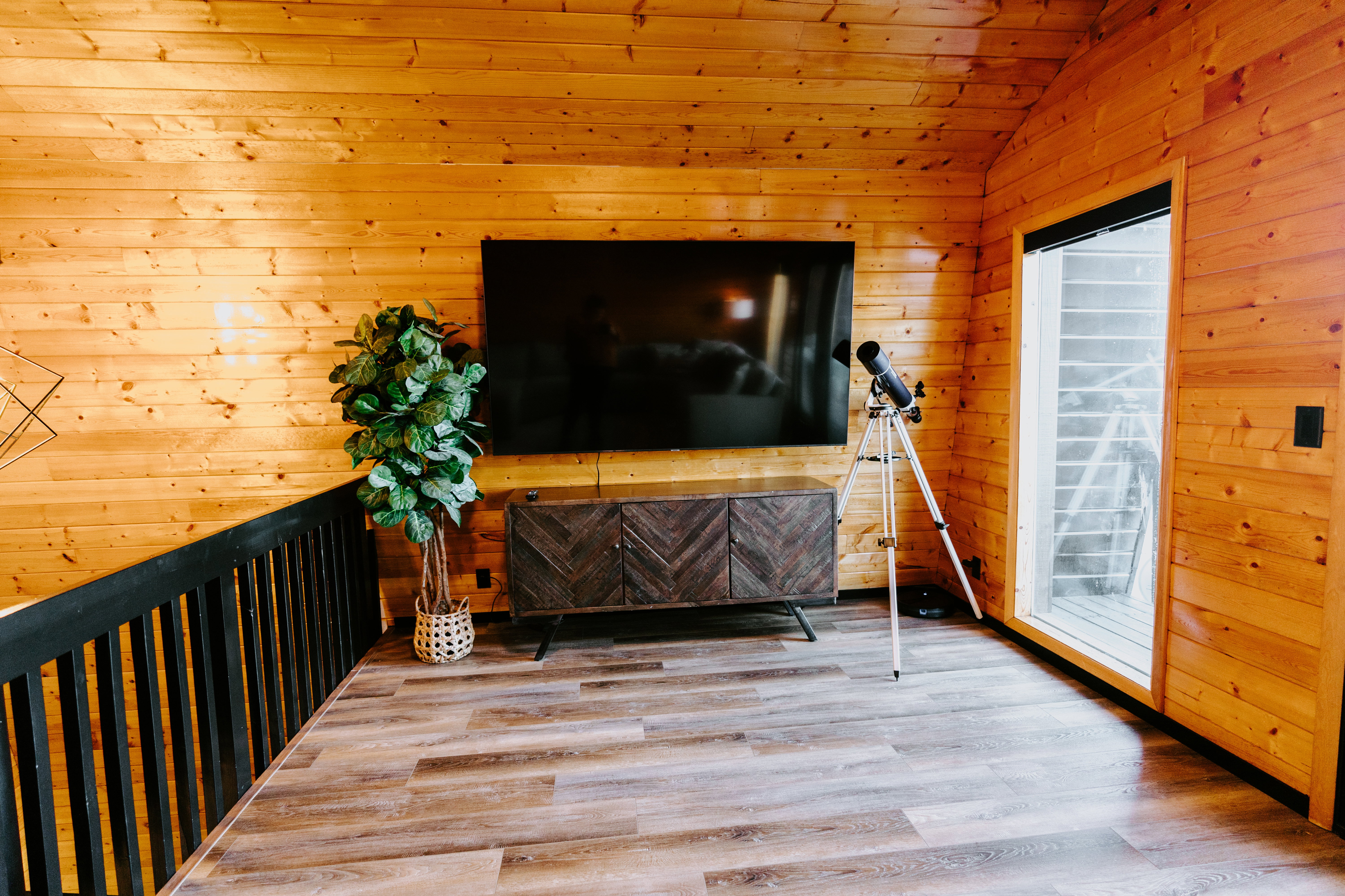 Living area featuring wooden walls, light wood-style flooring, and a vaulted wooden ceiling