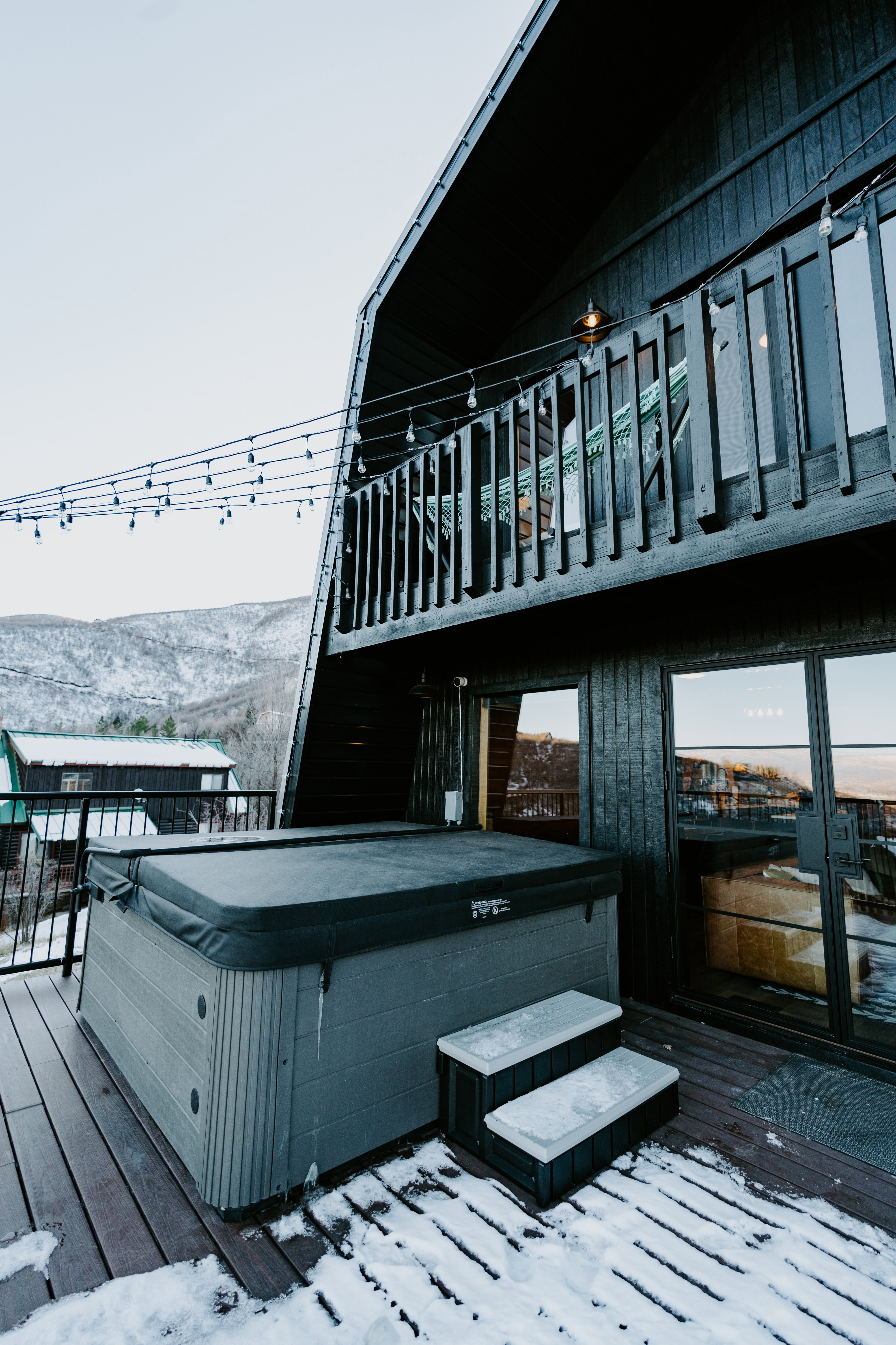 Snow covered deck with a hot tub and a mountain view