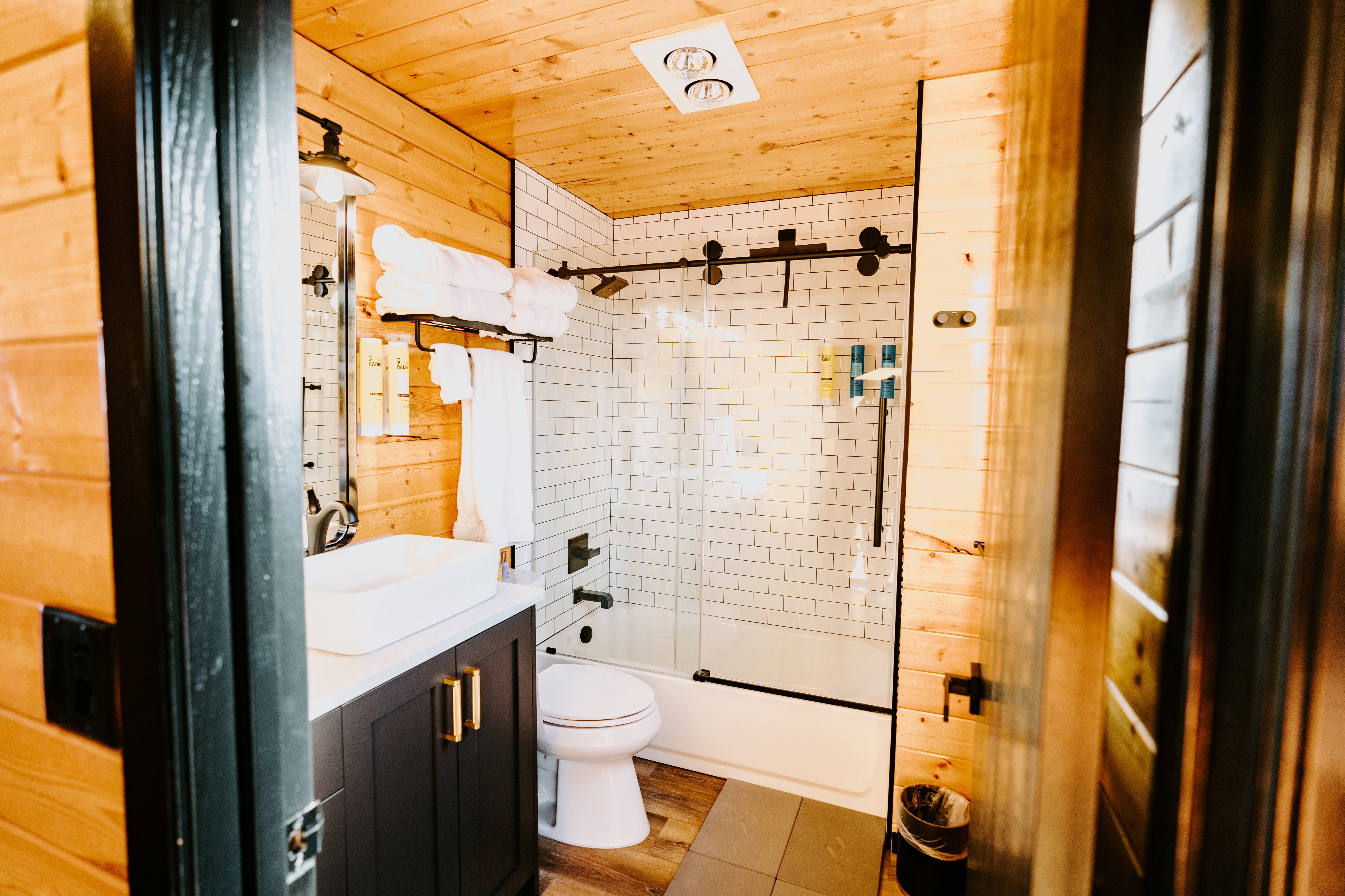 Full bath with vanity, enclosed tub / shower combo, wood walls, wooden ceiling, and light wood-type flooring
