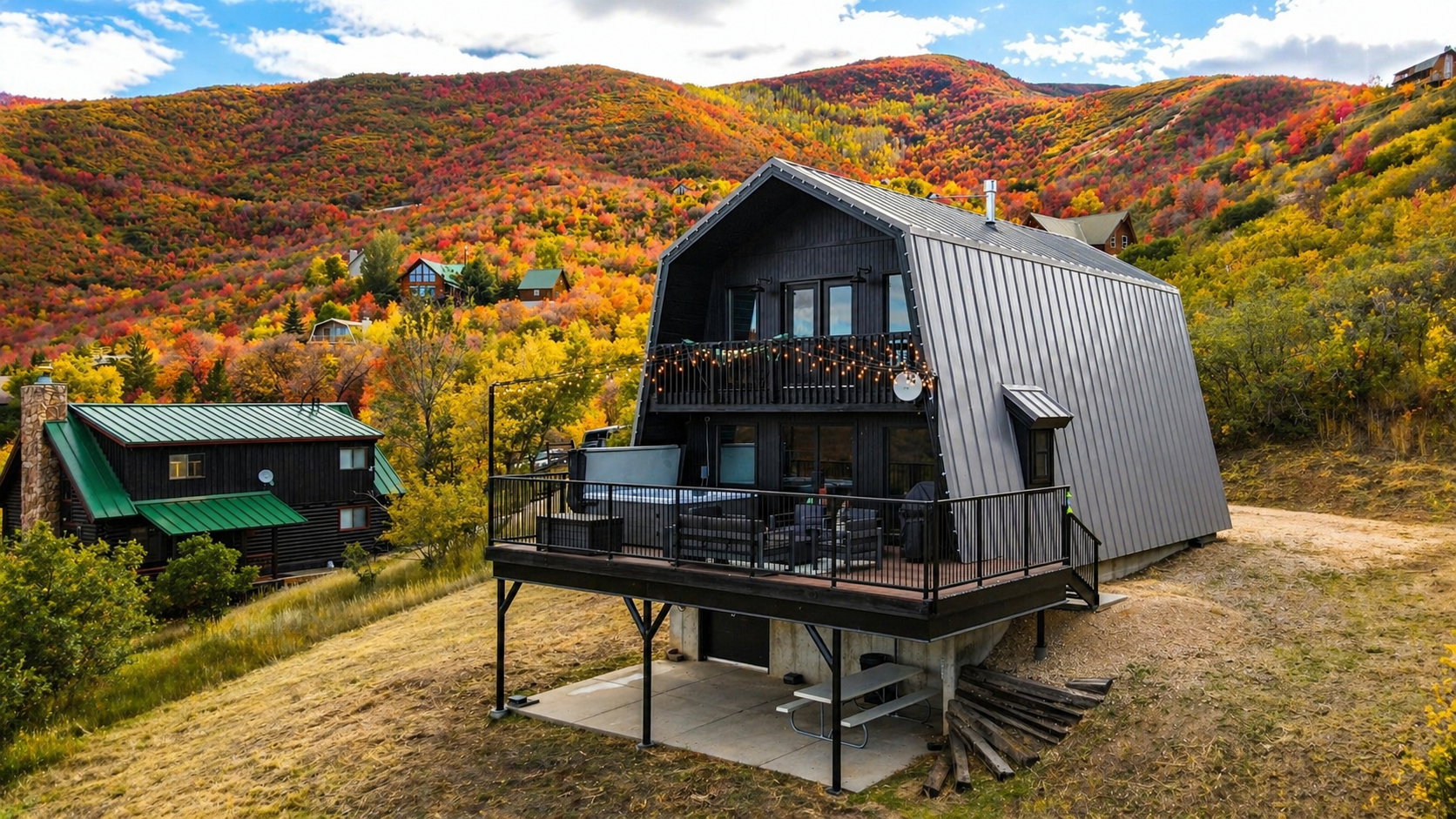 Rear view of house featuring a deck with mountain view, a patio, and a gambrel roof