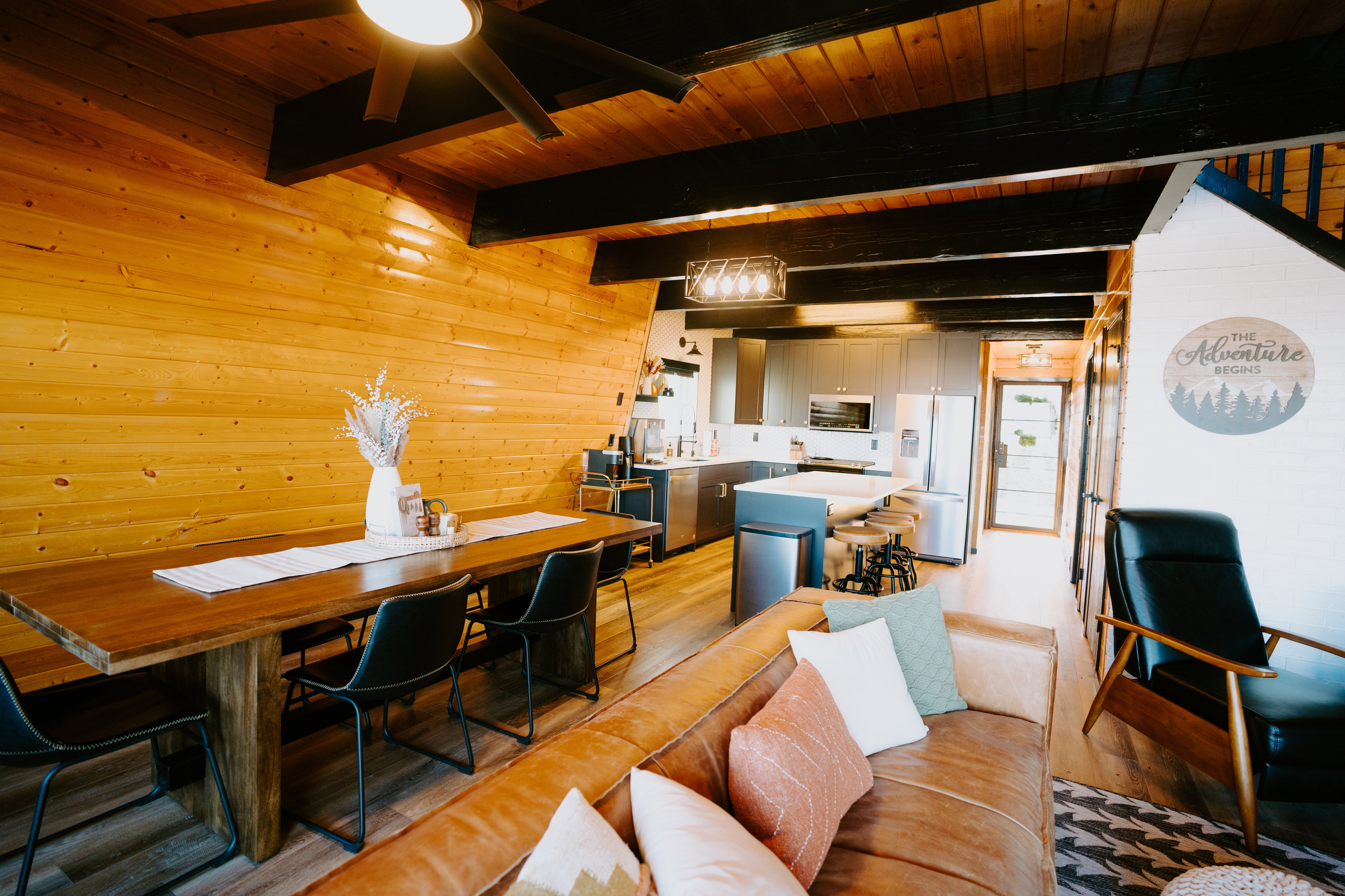 Living area with wooden walls, a wooden ceiling with exposed beams, light wood finished floors, and ceiling fan