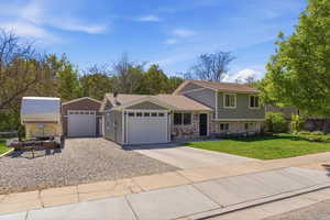 Split-level residence featuring a two-car attached garage, an additional detached single-car garage, and a gravel parking area