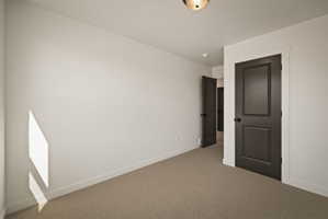 Unfurnished bedroom featuring carpet floors and baseboards