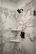 Full bath featuring a marble finish shower