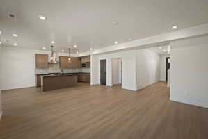 Kitchen with open floor plan, a kitchen island with sink, dark countertops, backsplash, and decorative light fixtures