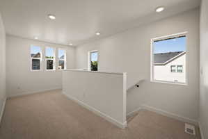 Hallway featuring carpet flooring, an upstairs landing, and recessed lighting