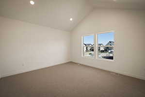 Spare room featuring dark colored carpet, a high ceiling, and recessed lighting