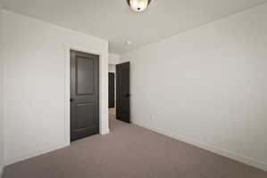 Unfurnished room featuring baseboards and light carpet
