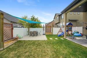 Expansive backyard featuring a manicured lawn, a paved patio area, Sail Shaded Area and a white privacy fence