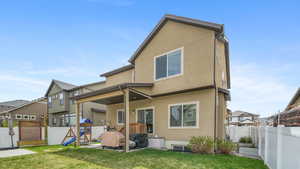 Rear view of house featuring a fenced backyard, stucco siding and a patio area