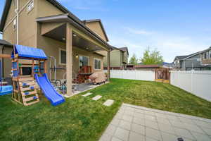 Expansive backyard featuring a manicured lawn, a large paver patio, stepping stones, a covered patio area with recessed lighting, and a white vinyl privacy fence
