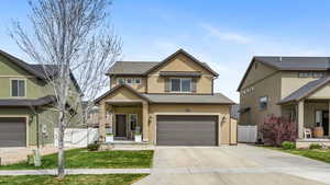 Traditional-style home featuring stucco siding, a gate, an attached garage, driveway, and roof with shingles