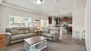 Living room with recessed lighting, a textured ceiling, a tray ceiling, and dark carpet