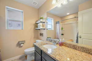 Bathroom featuring a granite-look countertop with an undermount sink, a dark wood-finish vanity, and a full-width mirror