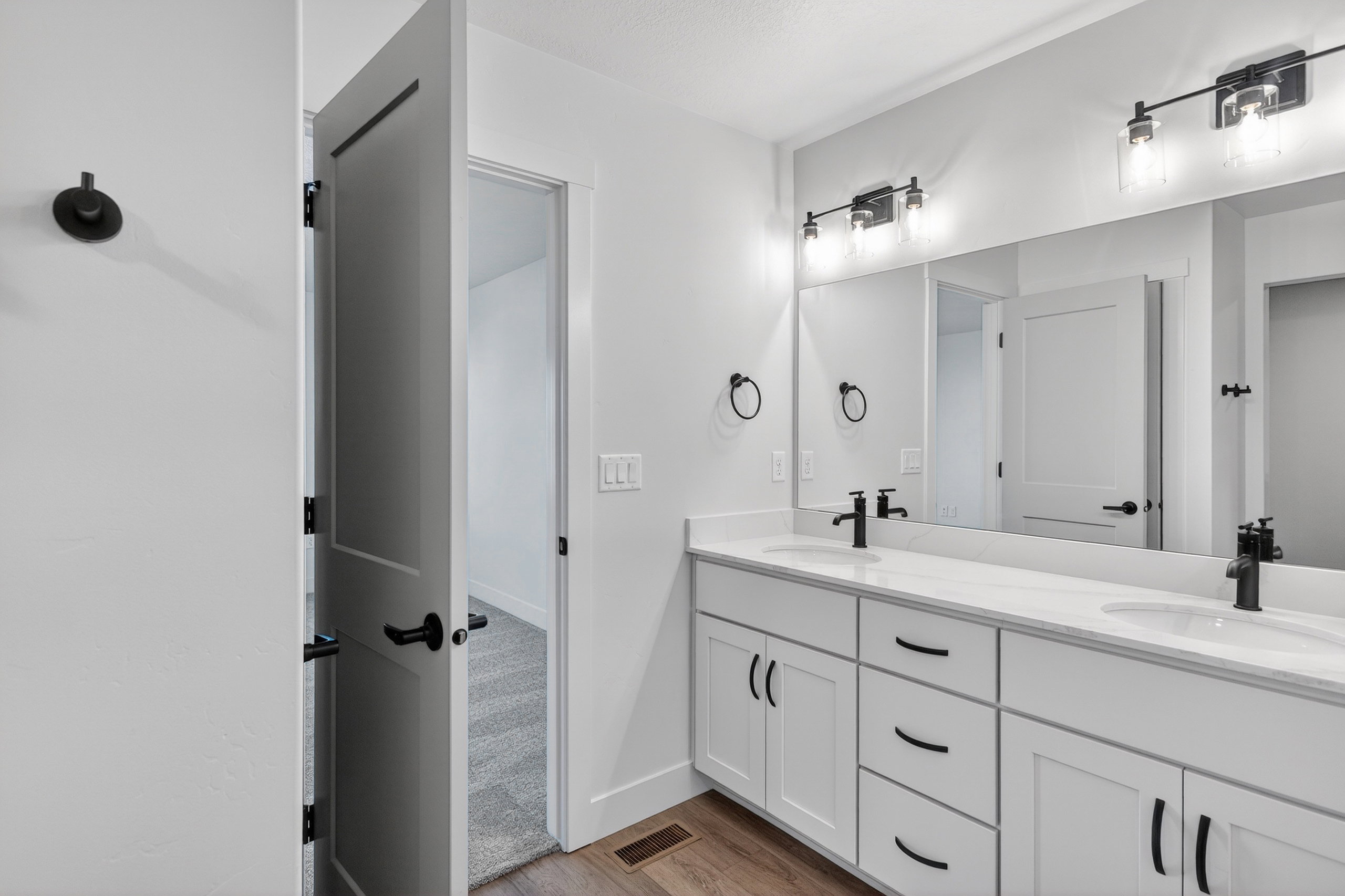 Bathroom with double vanity and dark wood-type flooring