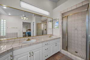 Bathroom featuring ensuite bath, a stall shower, double vanity, ceiling fan, and light tile patterned floors