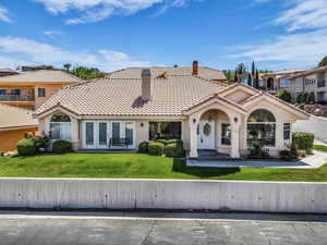 View of front of home featuring a chimney, stucco siding, a tiled roof, a front yard, and french doors