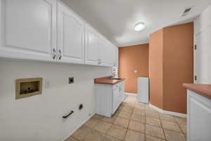 Laundry area with electric dryer hookup, a textured ceiling, cabinet space, hookup for a washing machine, and hookup for a gas dryer