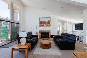 Living room with carpet floors, a fireplace, and a high ceiling