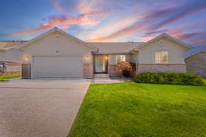 Single story home with an attached garage, concrete driveway, brick siding, and stucco siding