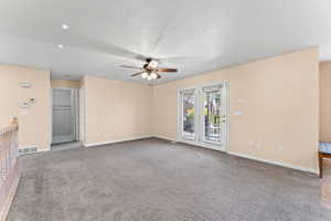 Unfurnished room featuring carpet, ceiling fan, and a textured ceiling
