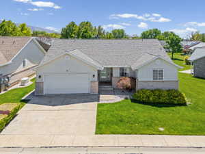 Ranch-style home with a front lawn, a garage, concrete driveway, brick siding, and stucco siding