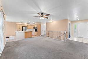 Unfurnished living room with light tile patterned floors, recessed lighting, light carpet, a ceiling fan, and a textured ceiling