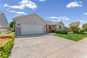 Ranch-style house featuring an attached garage, concrete driveway, a front lawn, and brick siding