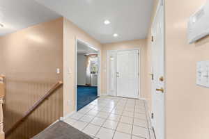 Entryway featuring light tile patterned floors and light colored carpet