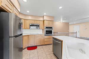 Kitchen featuring stainless steel appliances, light wood finish cabinets, recessed lighting, light countertops, and light tile patterned floors
