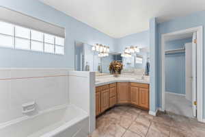 Full bathroom with double vanity, a garden tub, light tile patterned floors, a spacious closet, and light colored carpet