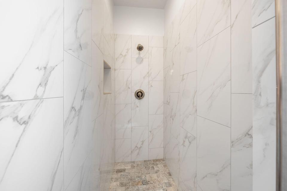 Full bath with a marble finish shower